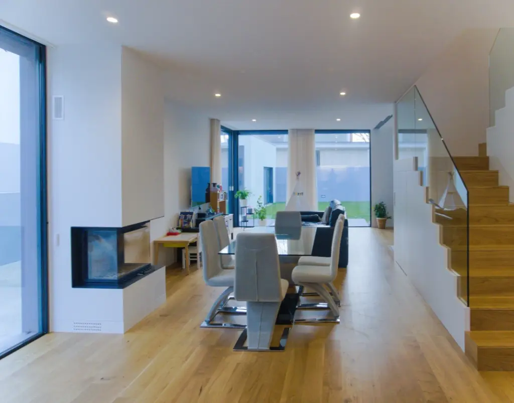 Dining room with a sitting area and children’s play area. The fireplace and the staircase leading to the upper floor are also visible.