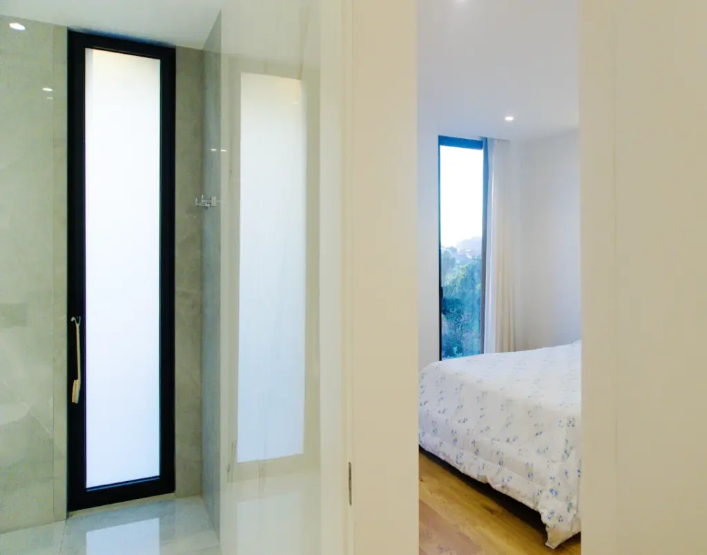 En-suite bedroom with a private bathroom and natural light from two windows.