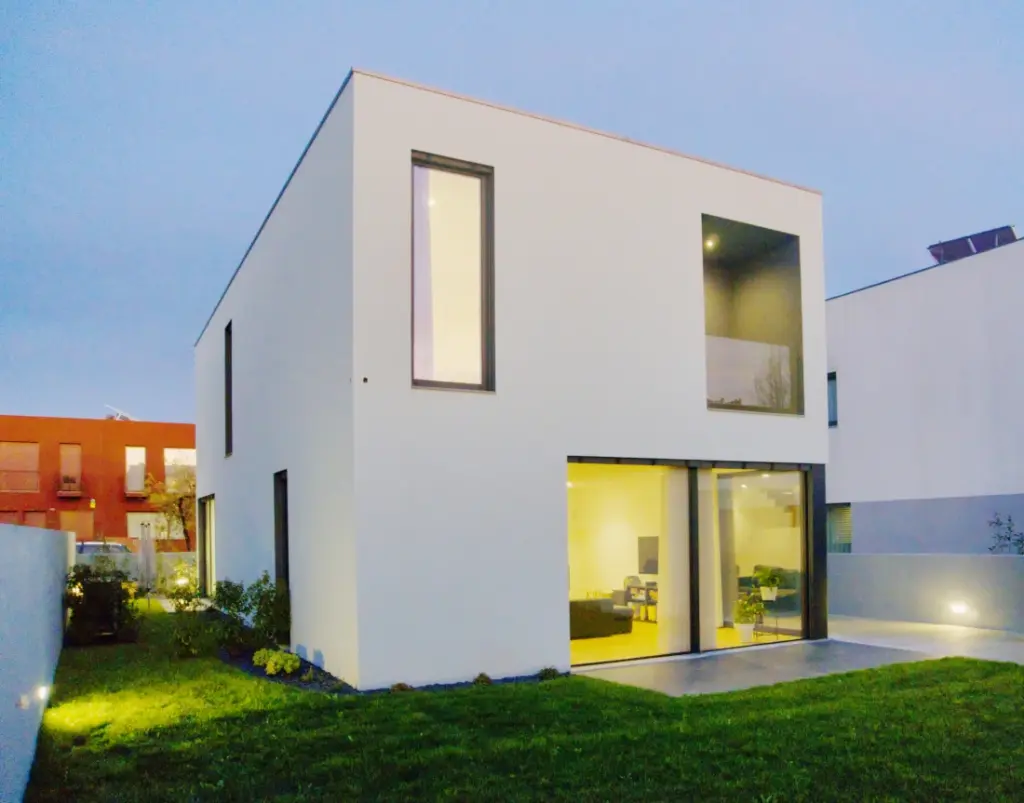 A house set within a lawned garden, with a terrace adjoining the living room windows.